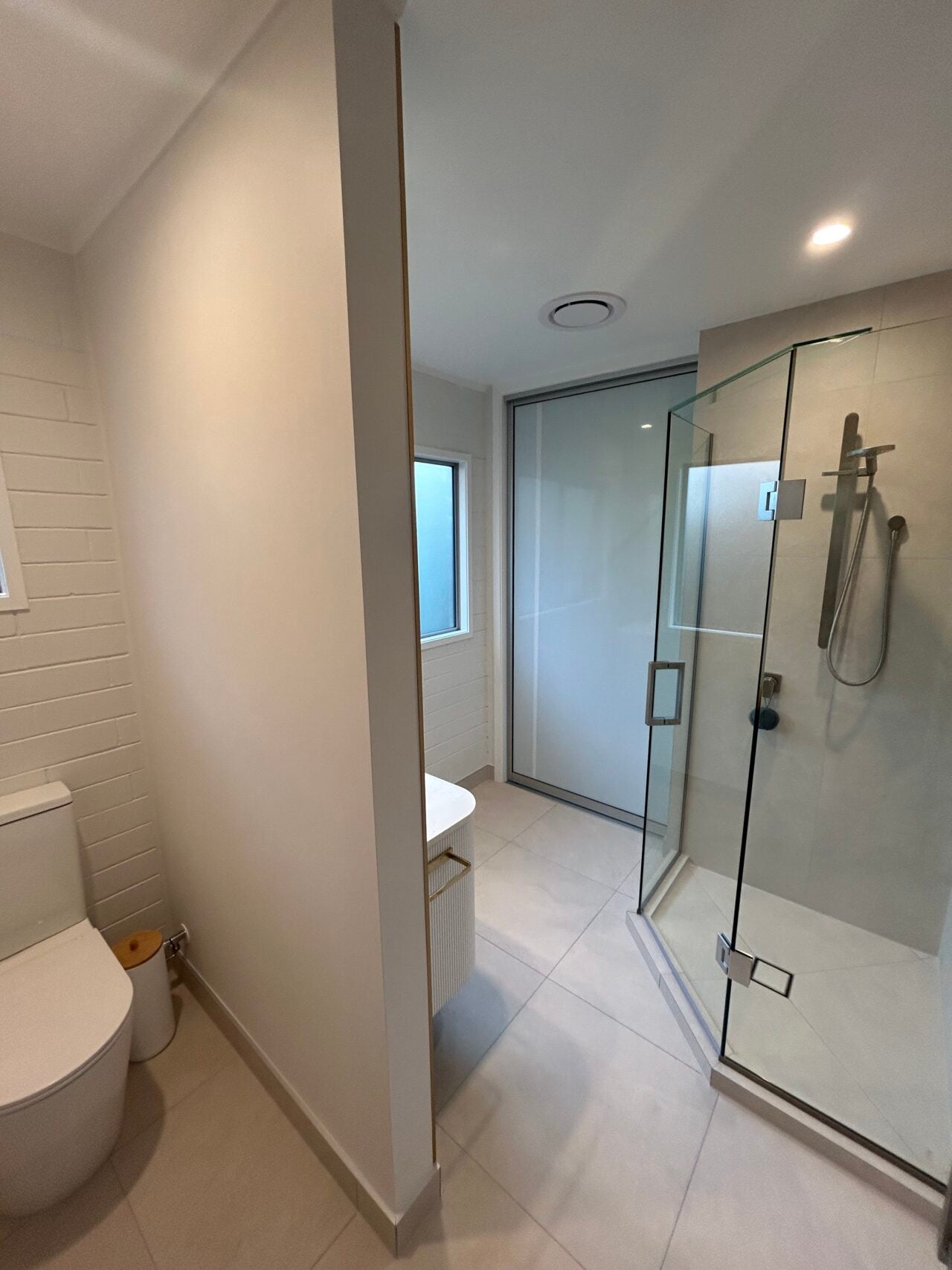 Luxury bathroom with tiled shower enclosure, frameless glass panels, and brass fixtures